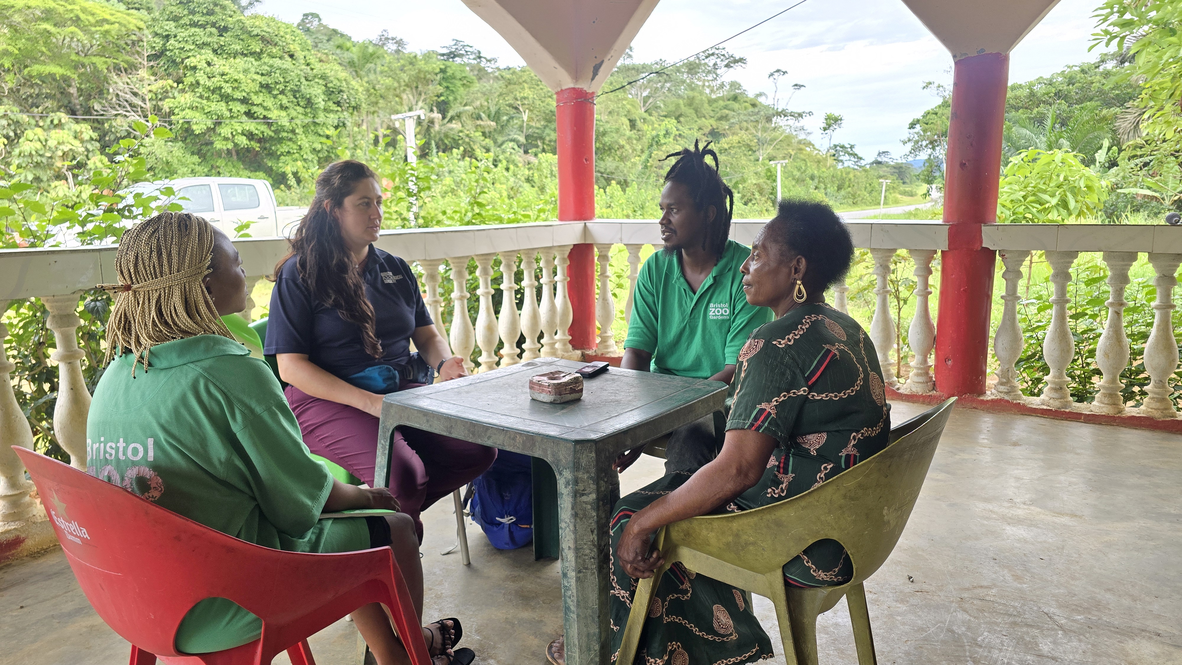 Four people sat around a table on a balcony in the forest