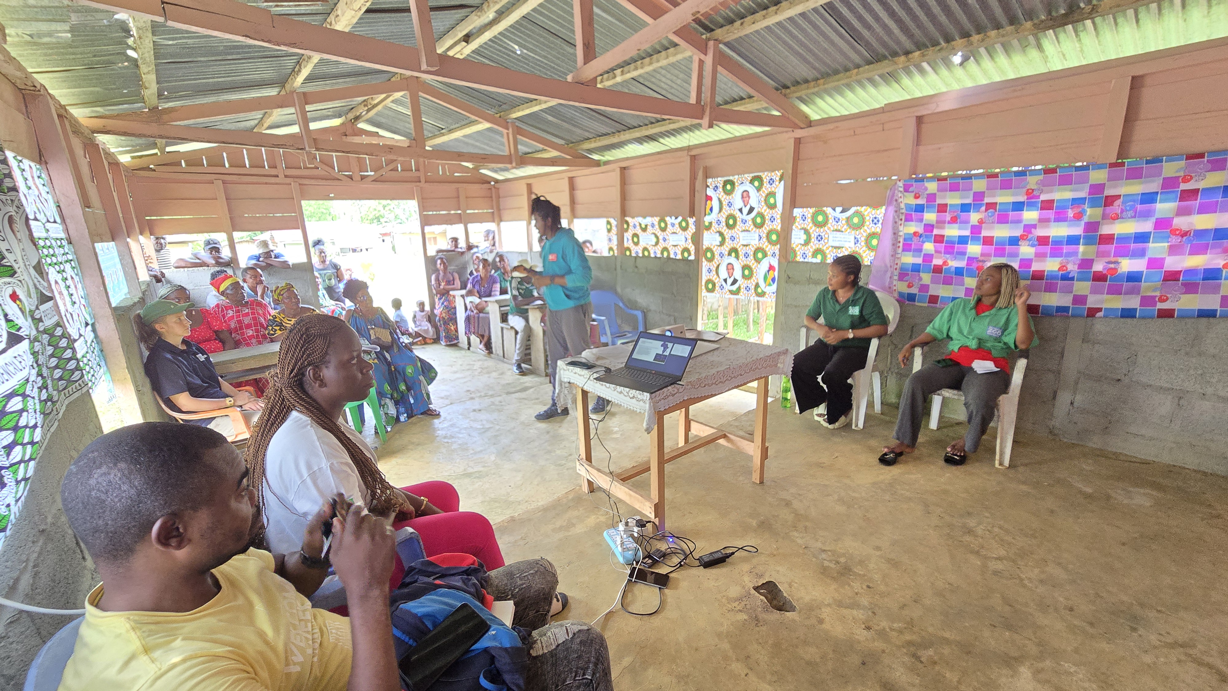 A group of people sitting and listening to a speaker in a community hall in Equatorial Guinea
