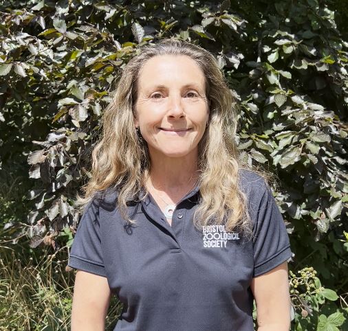 Lady smiling to camera wearing a Bristol Zoological Society t-shirt with a tree behind her.