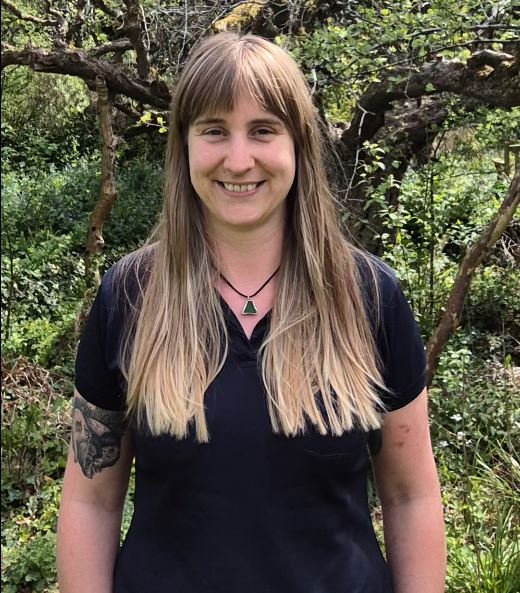 A person smiling in front of trees