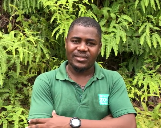 A man standing in a Bristol Zoo tshirt infront of a forest