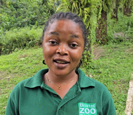 A woman standing in front of a green forest