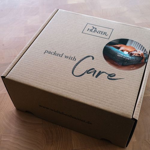 Brauner Karton mit dem „Hunter“-Logo, der Aufschrift „Mit Sorgfalt verpackt“ und einer runden Abbildung eines Hundes im Bett.