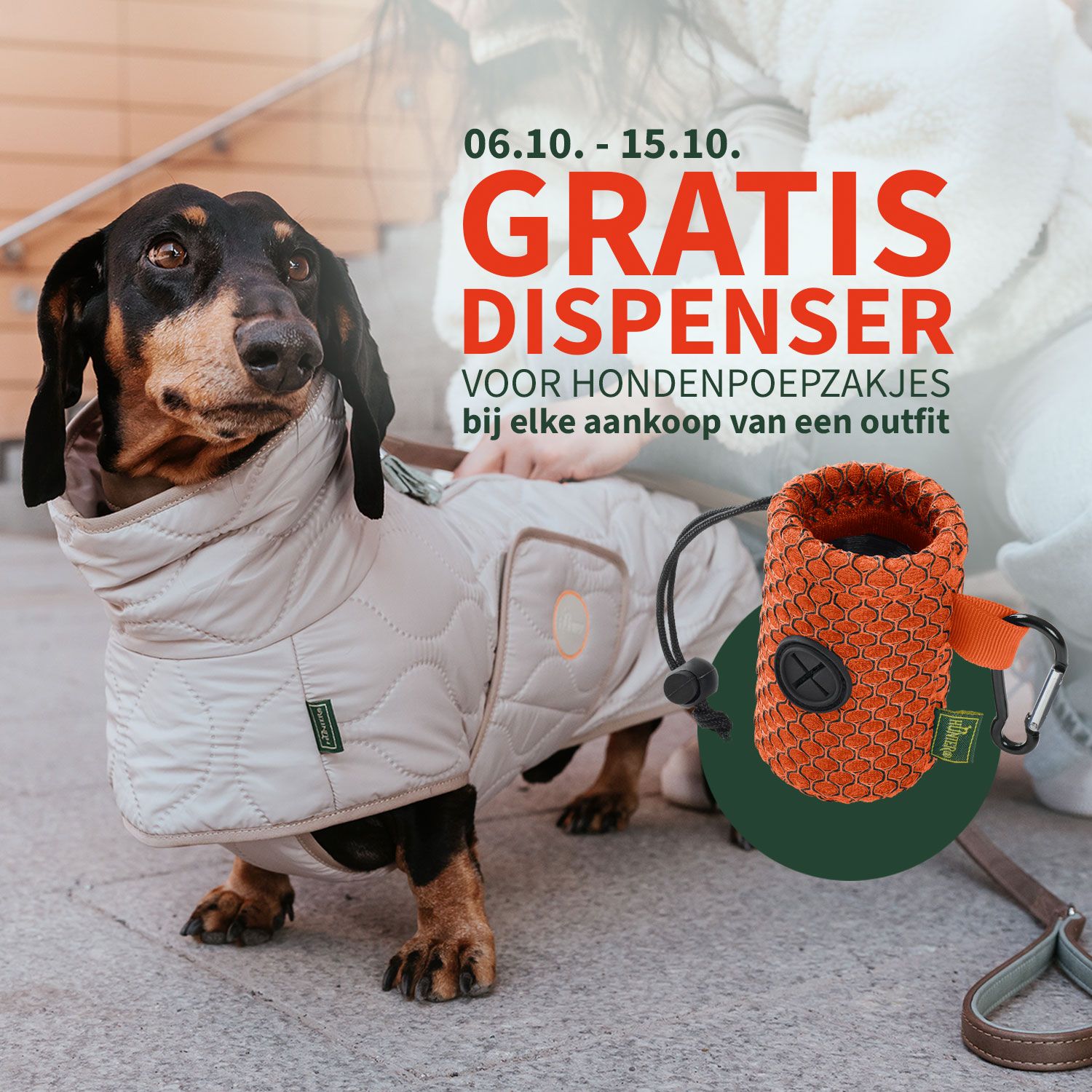 Een teckel in een gewatteerde jas aan de riem, reclame voor een gratis dispenser voor poepzakjes.