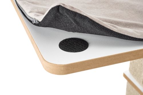 Detailaufnahme einer Kratzbaumplattform mit abnehmbarem Liegekissen, das per Klettpunkt befestigt wird; der Stoff ist leicht angehoben und zeigt die Befestigungstechnik.