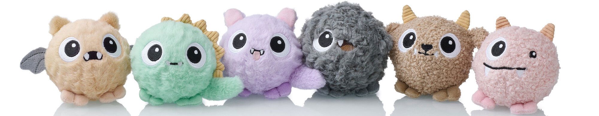 Eine Reihe von sechs runden Plüschtieren in verschiedenen Farben und mit unterschiedlichen Texturen sowie niedlichen Gesichtsausdrücken, von denen jedes einem kleinen Wesen oder Monster ähnelt.