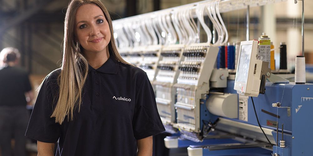 Embroiderer working on uniform logos at Alsico facilities.