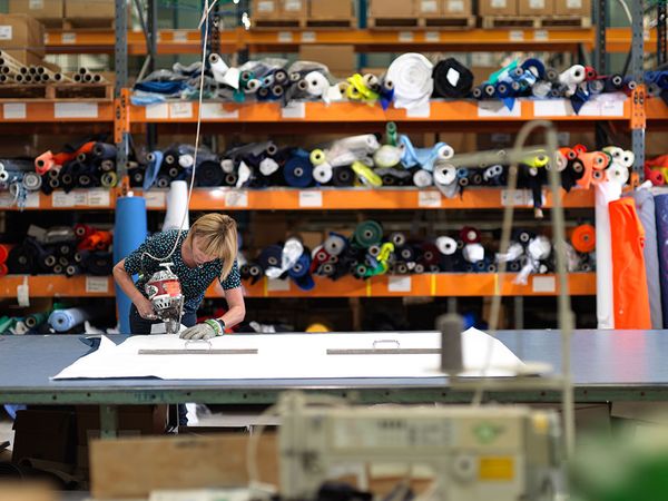 Worker cutting fabric for custom uniforms and healthcare garments.