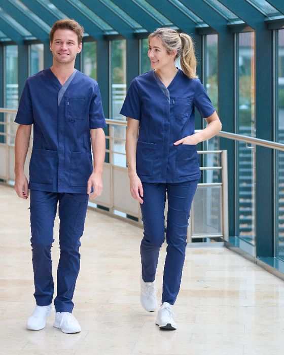 Two healthcare workers in Alsico's protective blue scrubs, designed for flexibility.