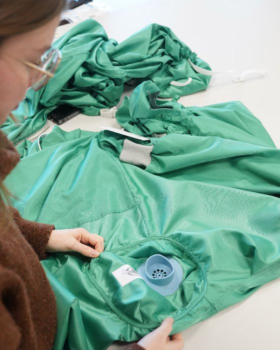 Worker inspecting cleanroom garment in Alsico contamination control line.
