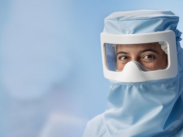 Person in cleanroom suit working with equipment, showing Alsico's PPE applications.