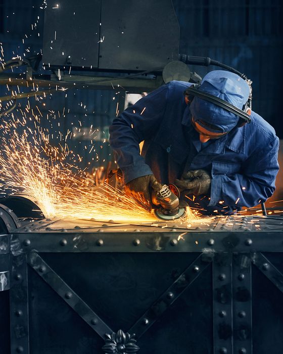 Bright sparks flying from industrial metalwork, highlighting welding PPE and safety gear.