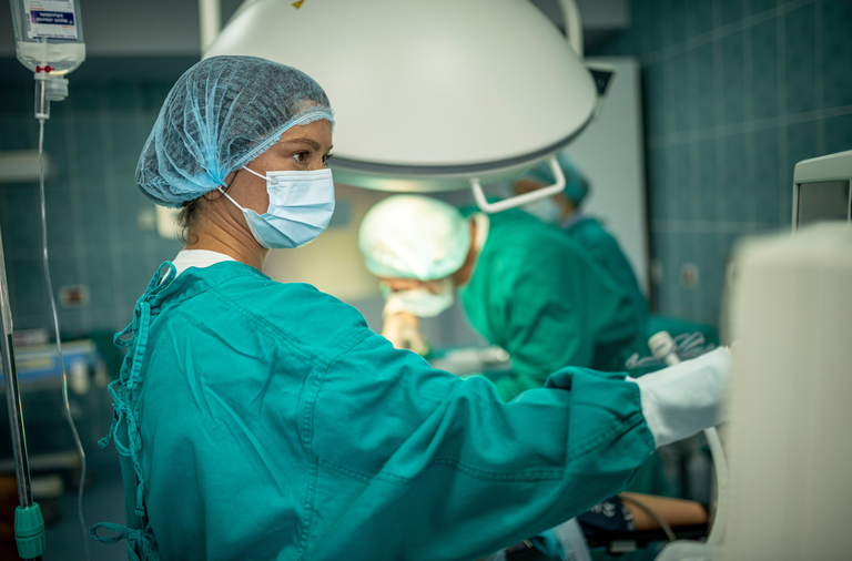 Healthcare professionals in an operating room, dressed in sterile protective uniforms.
