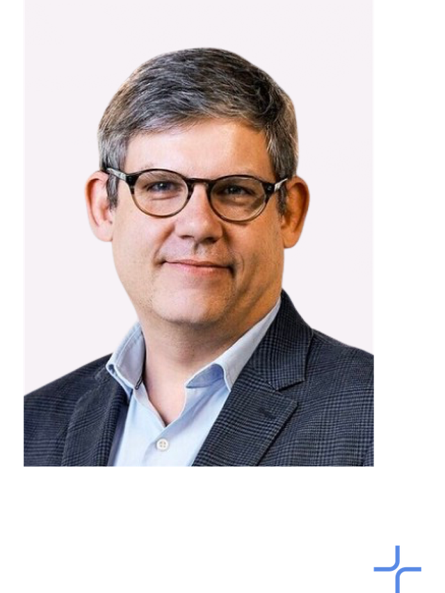 Chris Woodill wears a dark blue suit coat and a blue button up.