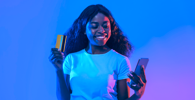Woman smiling while holding smartphone and credit card