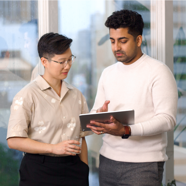 Two Apply Digital employees talking in the office over an iPad