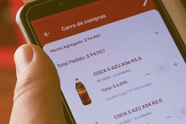 Hand holding a phone with the Coca Cola app open with an order for a bottle of Coca Cola