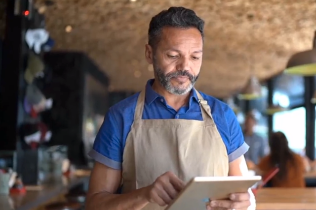Male barista at a coffee shop putting in an order on his ipad