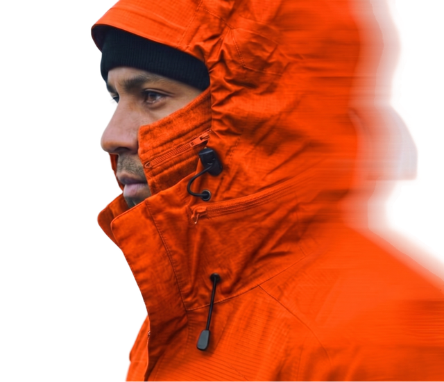A person in a vibrant orange jacket with a hood and black beanie, looking forward, surrounded by a blurred effect on the right side.
