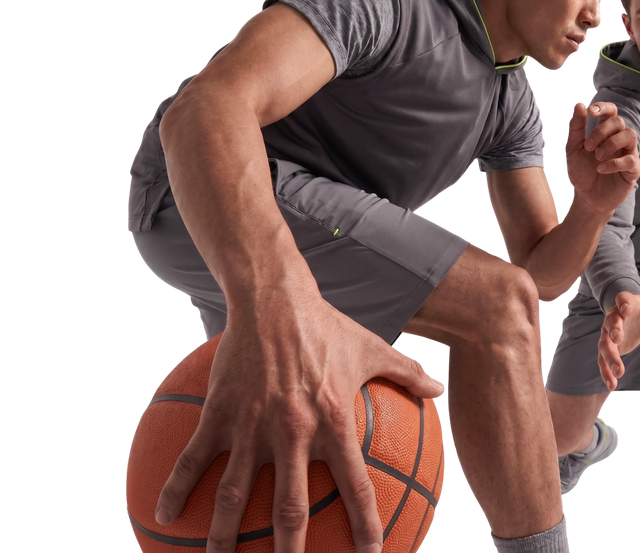 Athlete in gray sportswear dribbling a basketball, captured in an action pose on a black background.
