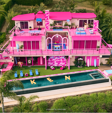 Airbnb Barbie mansion  with "KEN" by the poolside, featuring balconies, a basketball hoop, and palm trees surrounding the property.