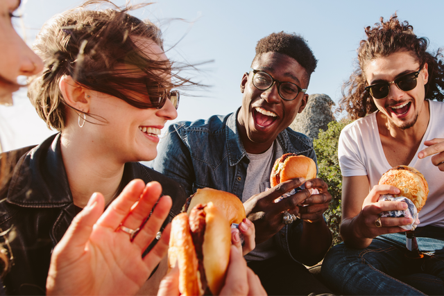 A group of four friends eat their burgers together.