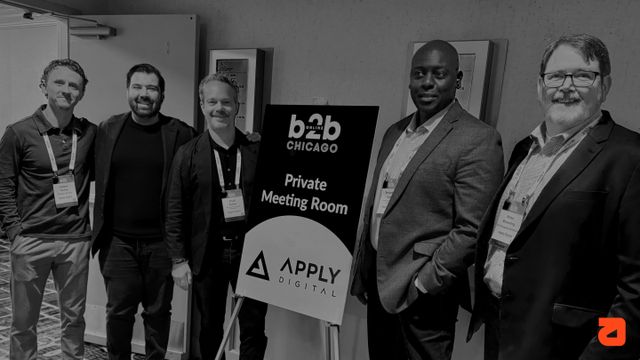 Five men posing by a "b2b Chicago Private Meeting Room" sign, wearing conference badges.