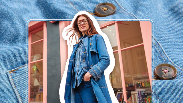 A woman wears a long denim coat, a chambrary shirt, and jeans.