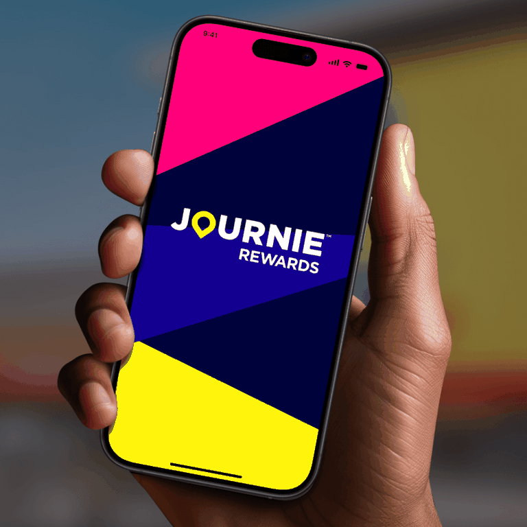 Hand holding a smartphone displaying the "Journie Rewards" app with a colorful geometric background.