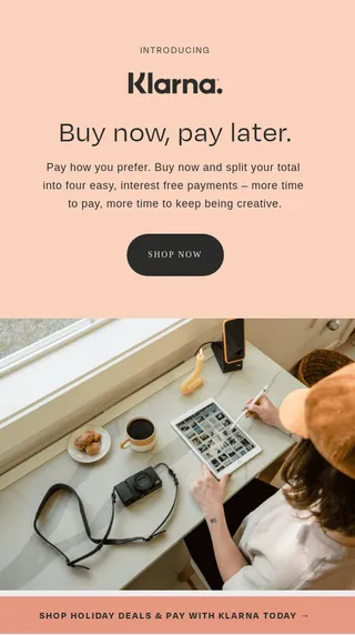 A person at a desk with a tablet, camera, and coffee. Text promotes Klarna's "Buy now, pay later" service.