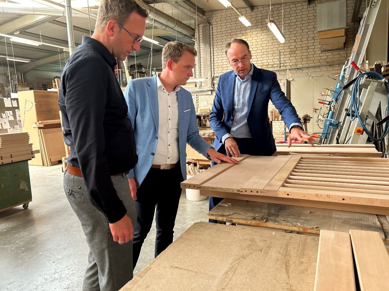 Wirtschaftsförderer Michael Terhörst (links) Bürgermeister, Dr. Tom Tenostendarp (Mitte) und Geschäftsführer Günter Bußmann in der Produktionshalle der SAVI Reha Solutions.