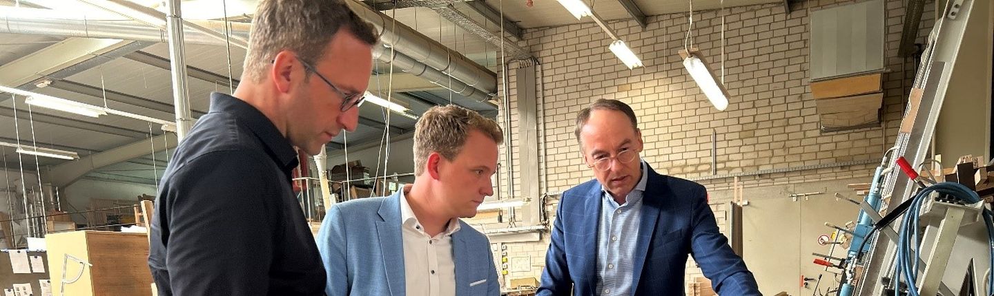 Wirtschaftsförderer Michael Terhörst (links) Bürgermeister, Dr. Tom Tenostendarp (Mitte) und Geschäftsführer Günter Bußmann in der Produktionshalle der SAVI Reha Solutions.