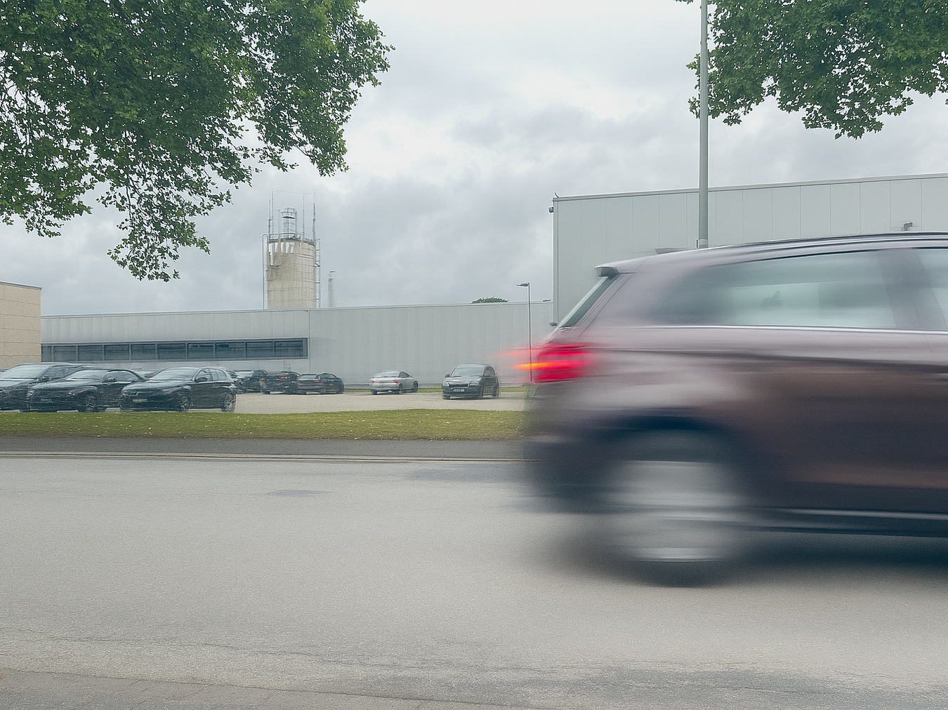 Verschwommenes Heck eines Autos vor dem Industriegebiet.
