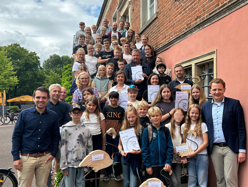 Gruppenbild aller Teilnehmenden der Siegerehrung auf der Rathaustreppe