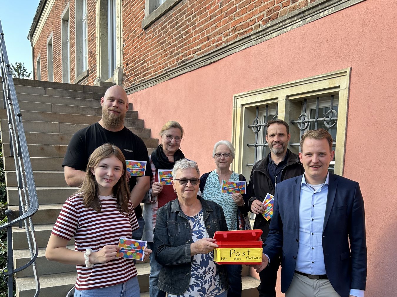 Mitglieder der Initiative „VREDEN BLEIBT BUNT“ übergeben die Wünsche, Fragen und Anregungen der Vredenerinnen und Vredener auf der Burgtreppe an den Bürgermeister Dr. Tom Tenostendarp.