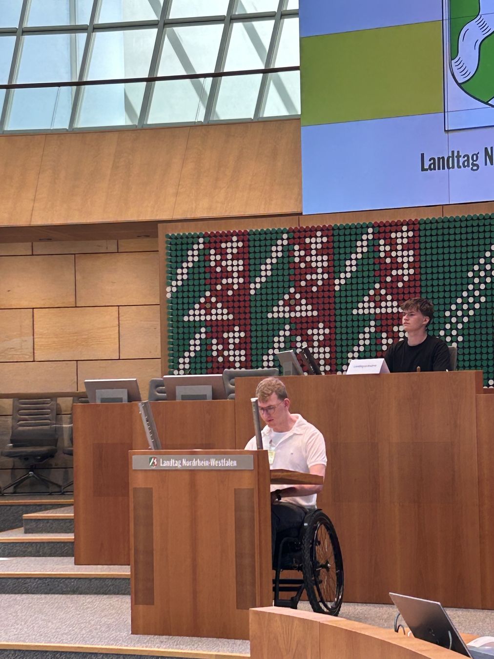 Auszubildender im Rollstuhl am Rednerpult des Landtags NRW