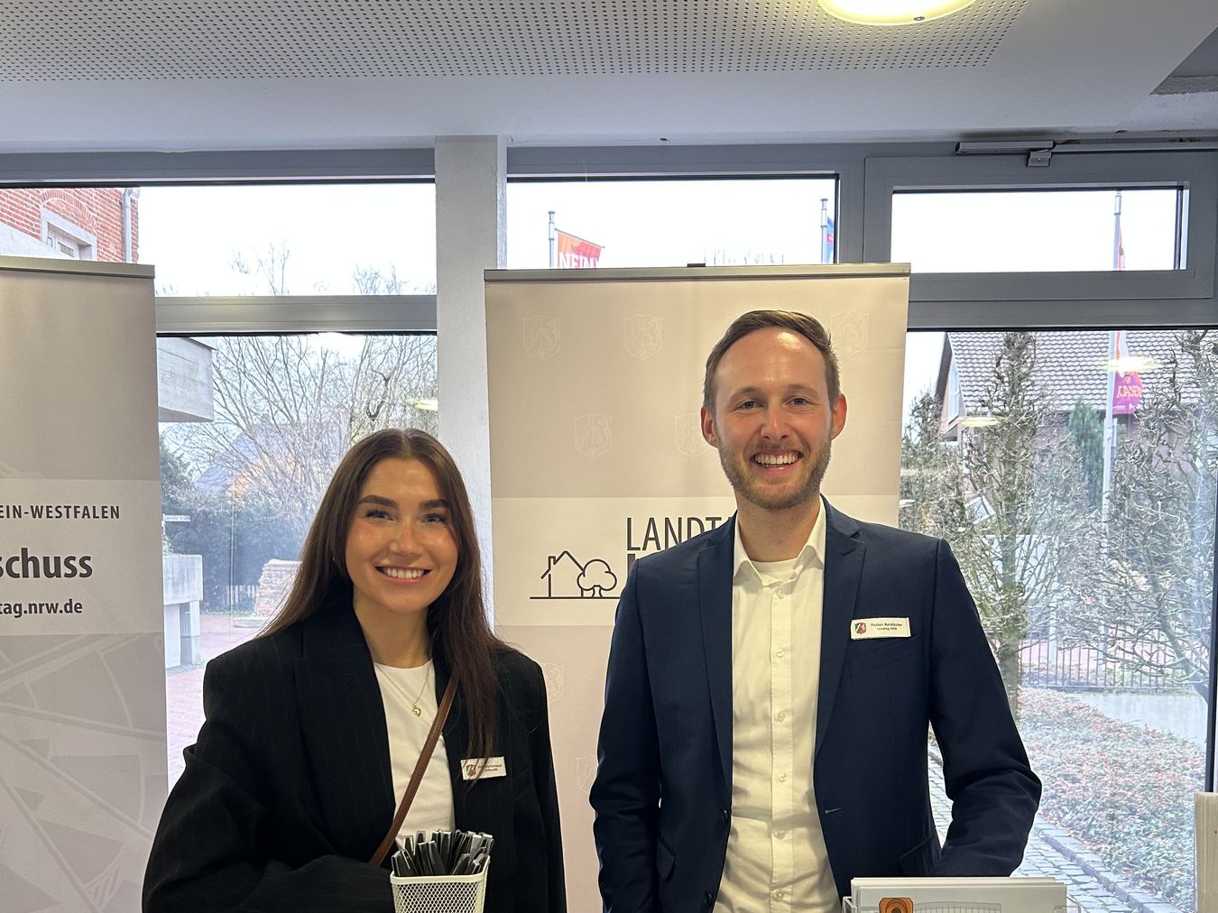 Mitarbeitende des Petitionsausschusses stehen mit einem Stand im Rathaus