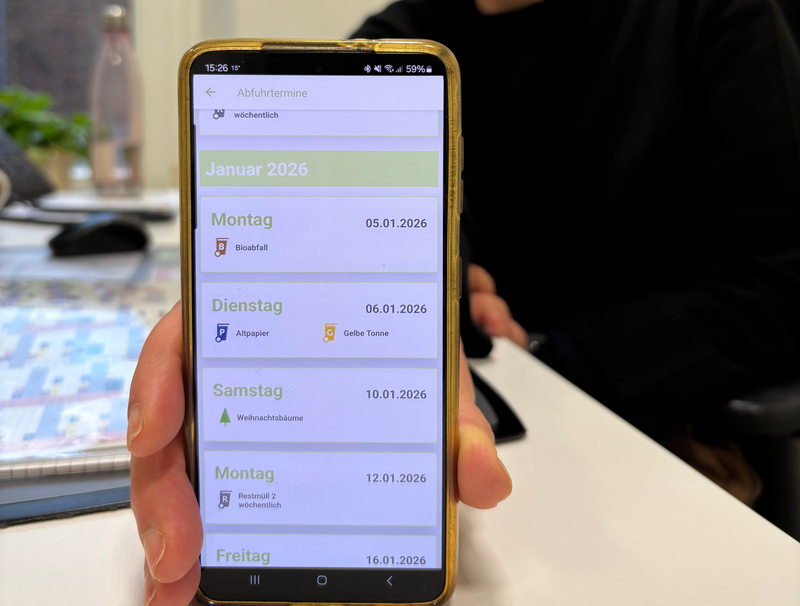 Eine Frau hält eine Handy mit der geöffneten EGW App in die Kamera