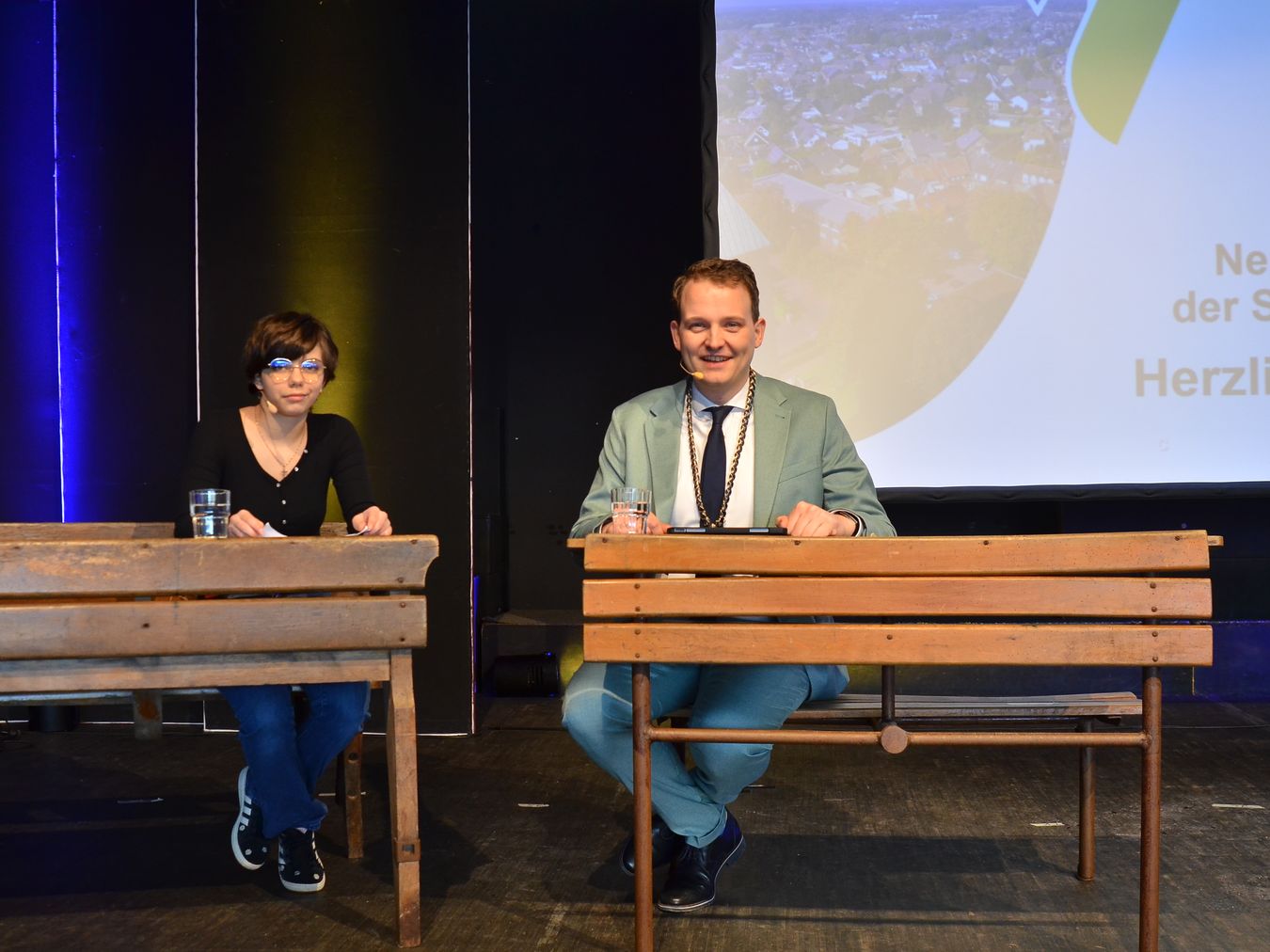 Leyla Mende und Bürgermeister Dr. Tom Tenostendarp gemeinsam auf einer alten Schulbank.