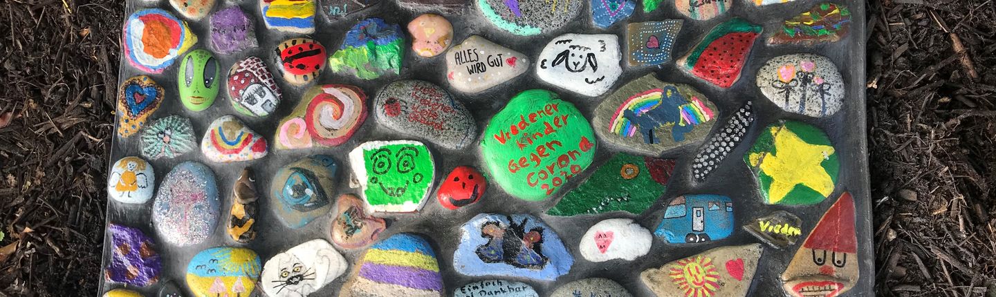 Mosaik aus bunten und von Kindern bemalten Steinen