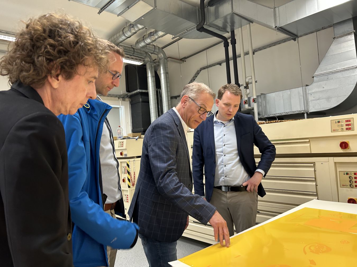 Die beiden Geschäftsführer der PROFILE Communication GmbH sowie Michael Terhörst und Bürgermeister Dr. Tom Tenostendarp schauen betrachten die Produktion.