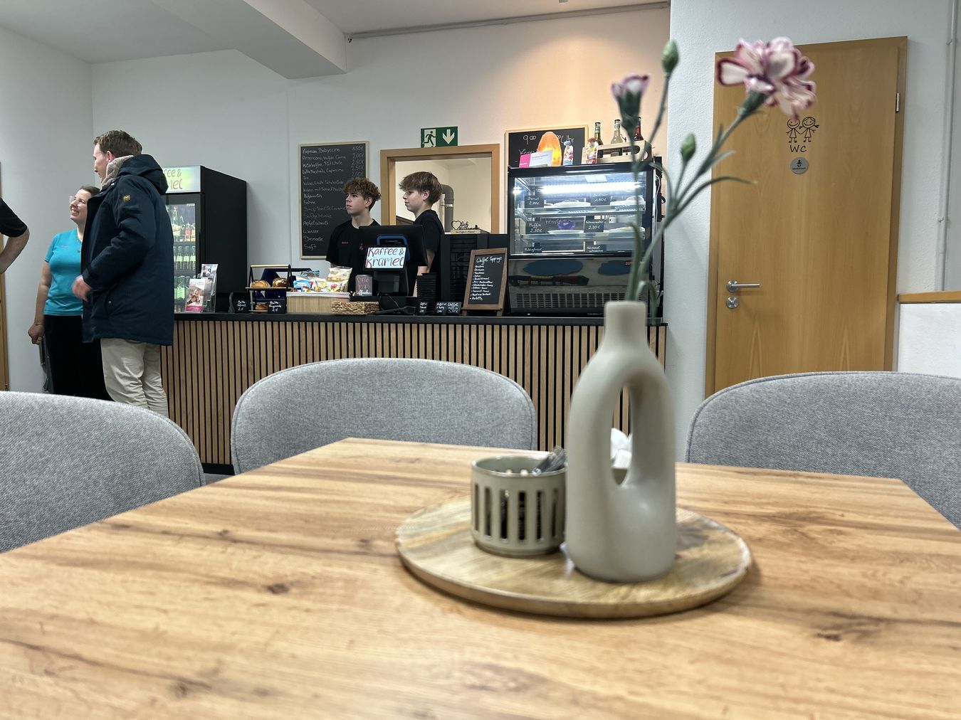 Bild eines Tisches mit Pflanze im Vordergrund. Im Hintergrund die Theke