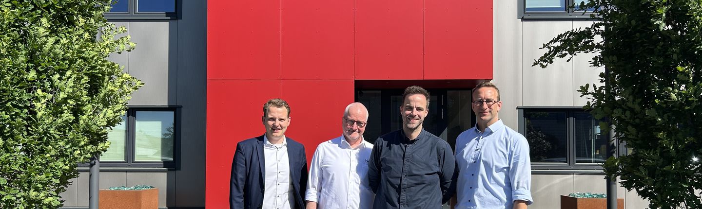 Es stehen vor dem Haake.Firmenlogo (v.l.n.r.): Bürgermeister Dr. Tom Tenostendarp, Geschäftsführer André Haake, Geschäftsführer Jonas Haake und Wirtschaftsförderer Michael Terhörst.