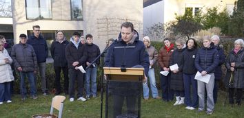 Bürgermeister Dr. Tom Tenostendarp steht an einem Pult vor einer Gruppe Vredenerinnen und Vrednener und hält eine Rede zum Jahrestag der Befreiung Auschwitz