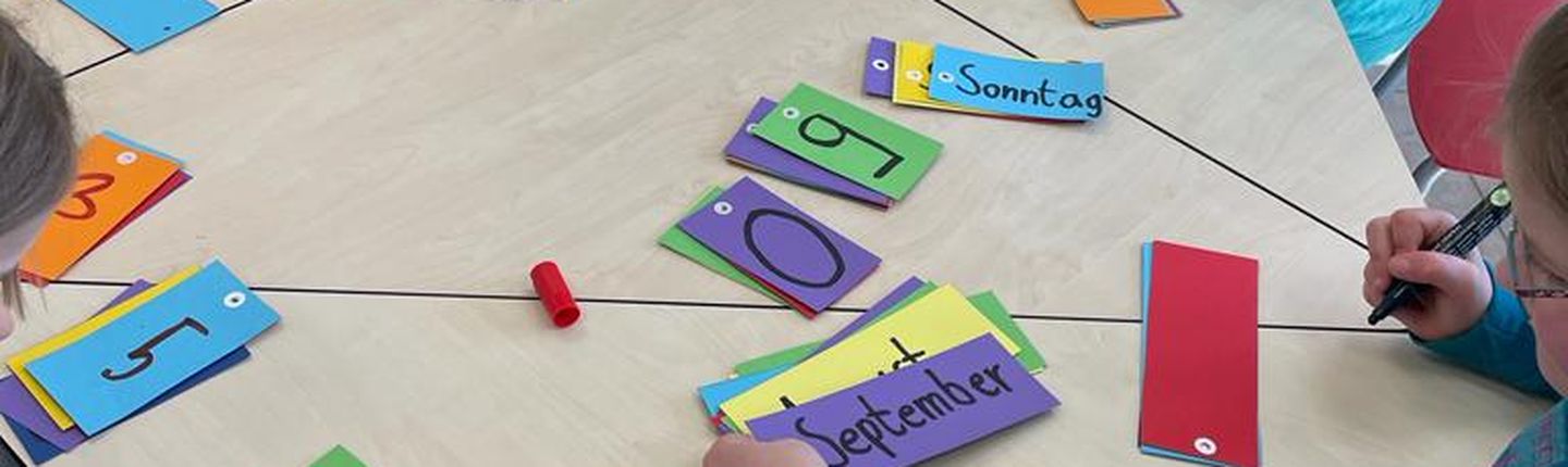 Kinder sitzen an einem Tisch und basteln.