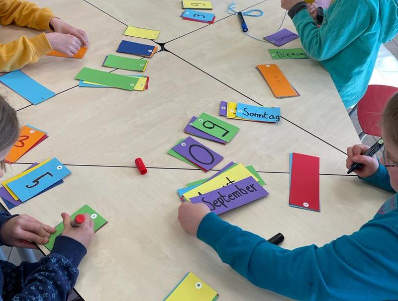 Kinder sitzen an einem Tisch und basteln.