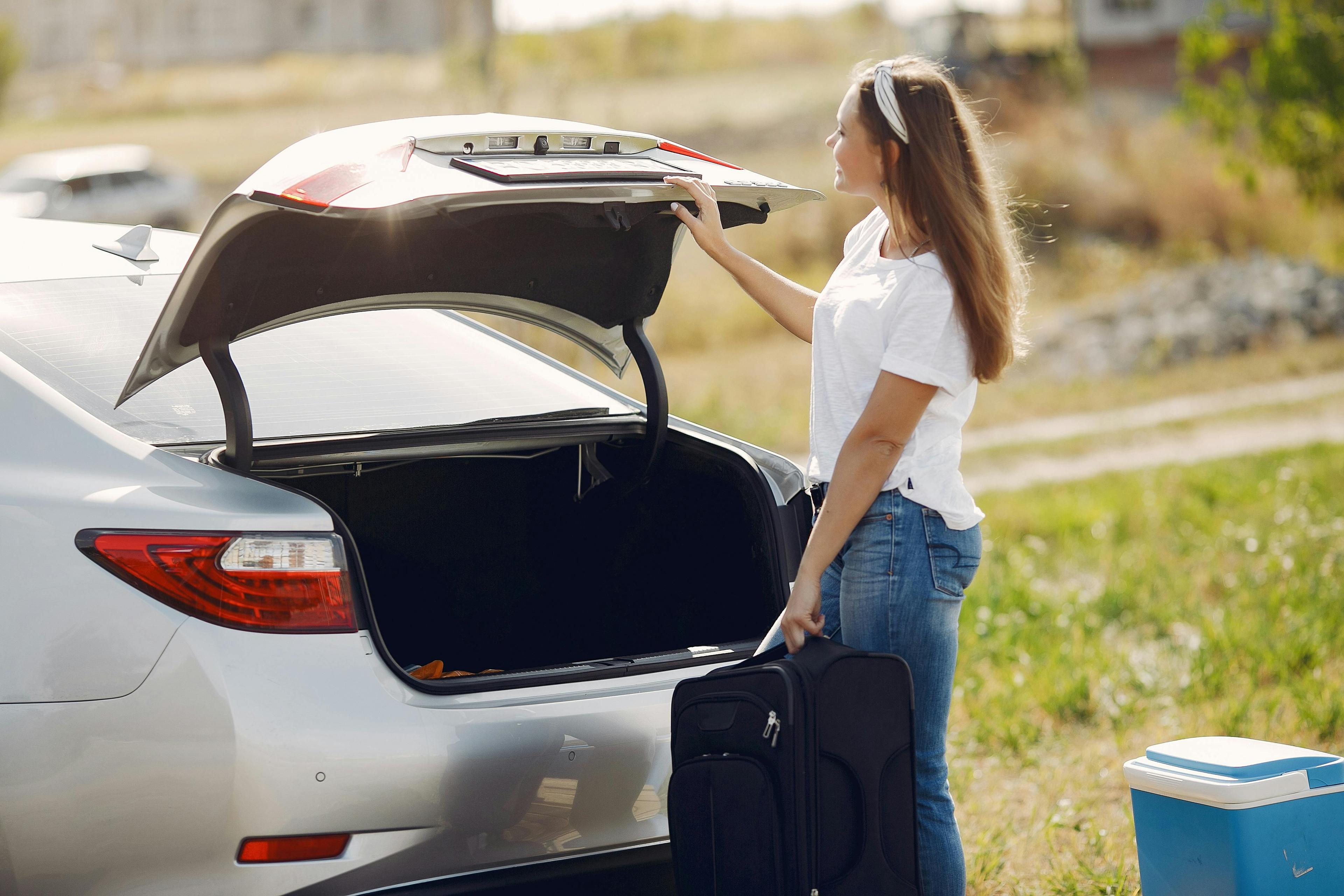 Vrouw laadt bagage in de koffer van de wagen.