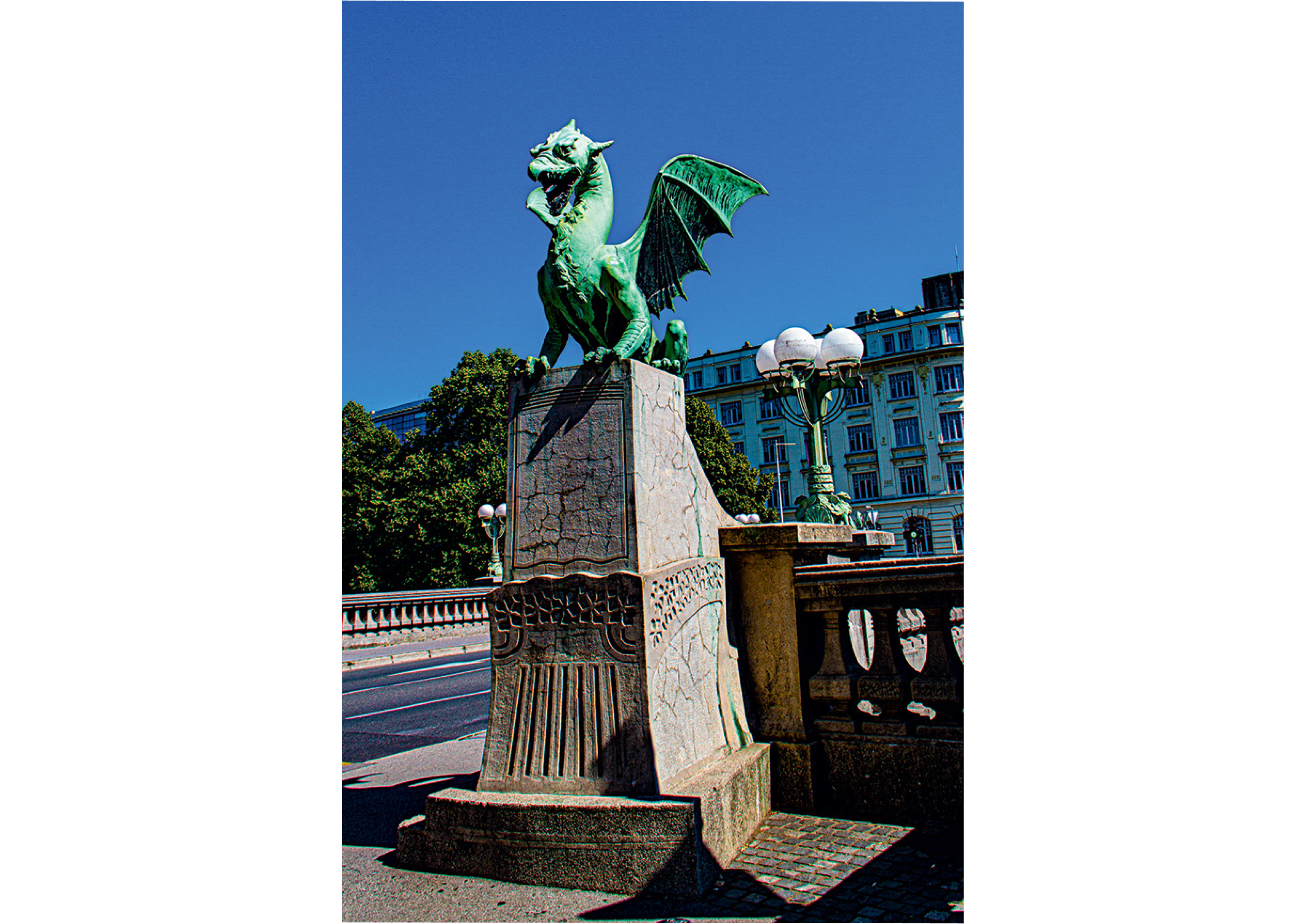 Statues of dragons Green dragon statue perched on a stone pedestal beside a road, with historic buildings and trees in the background.