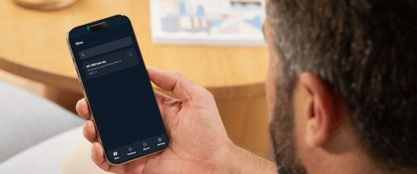 Person holding a smartphone displaying a dark-themed app interface with options for sharing, settings, and managing Wi-Fi networks.