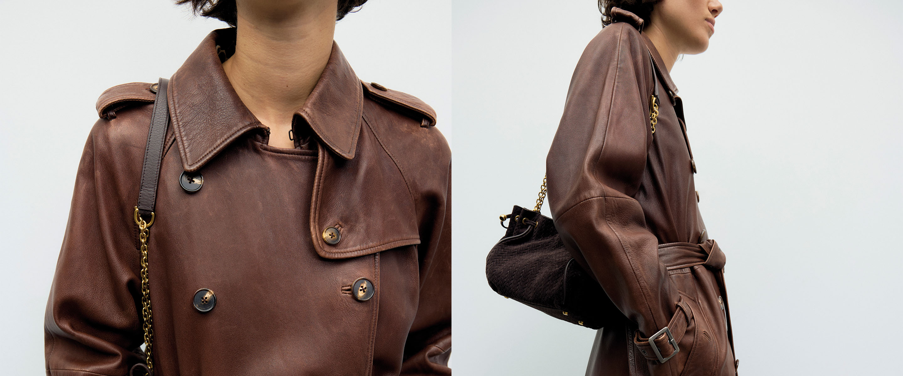 A person wearing a brown leather trench coat with shoulder straps and a dark woven bag with a chain strap.